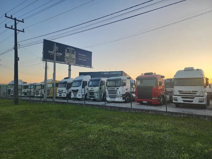 Pátio de frota do Grupo Trevo com caminhões estacionados ao entardecer